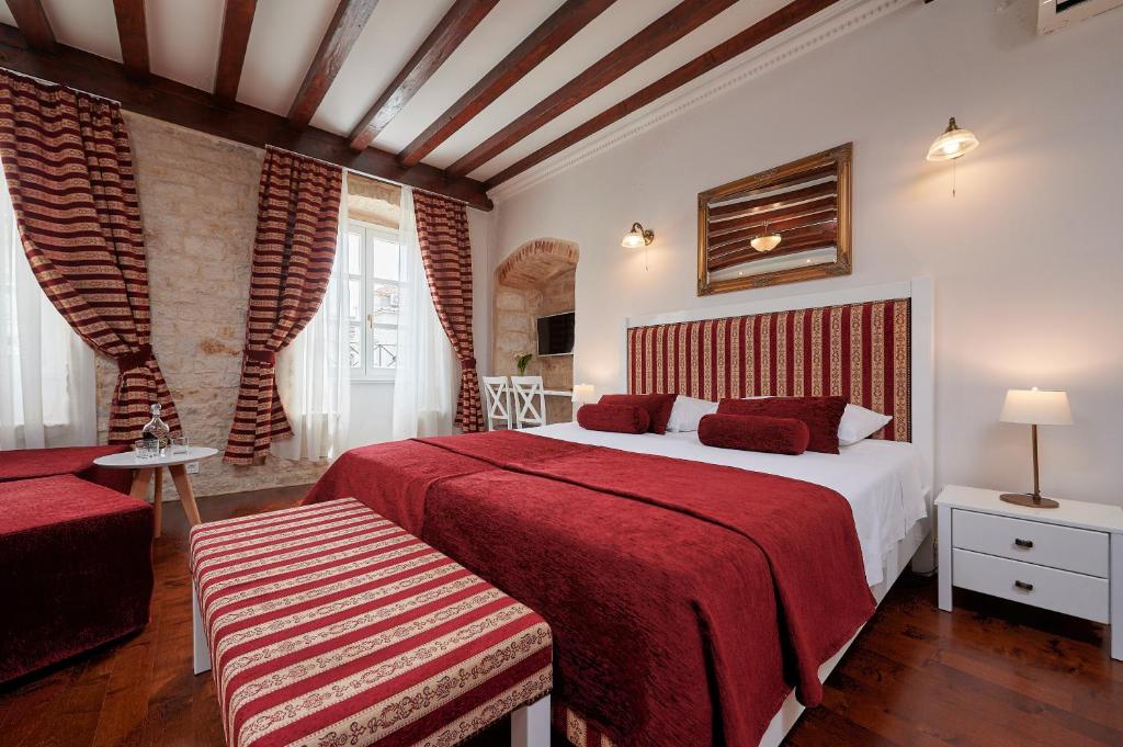 a bedroom with two beds with red sheets and a window at Palace Central Square in Trogir