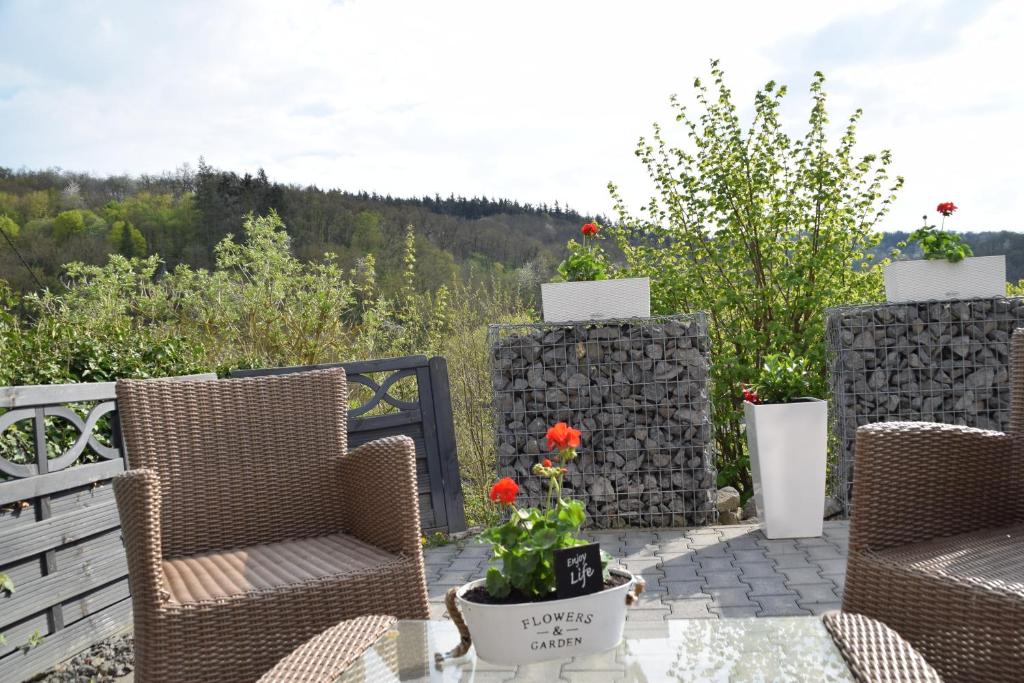 un patio con 2 sillas y una mesa con flores en Ferienwohnung Schieferpfad, en Trimbs