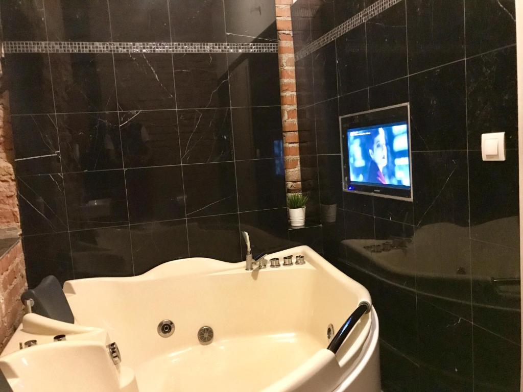 Brno center whirlpool apartment في برنو: حمام مع حوض استحمام وتلفزيون في الحمام