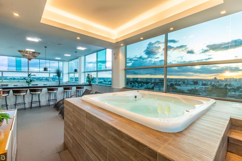 a large bath tub in a room with large windows at Porto Minas Hotel e Convenções in Uberlândia