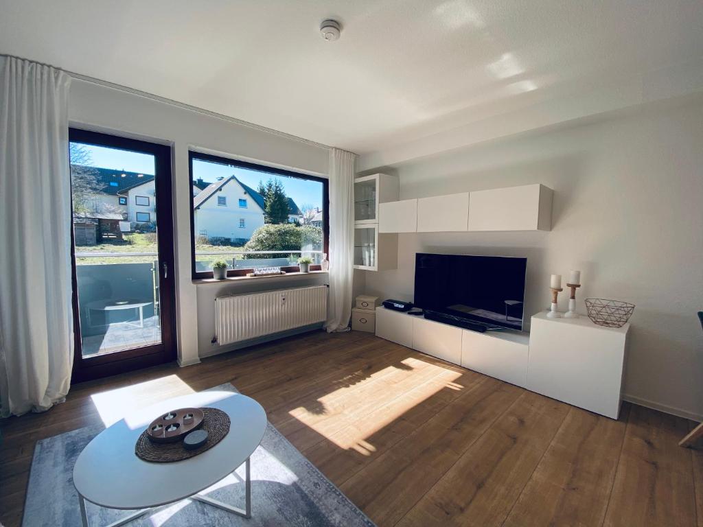 a white living room with a table and a tv at Ferienwohnung Sunside im Herzen von Winterberg in Winterberg