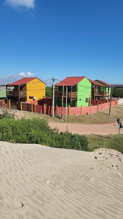 una fila de edificios coloridos en una playa en Cabañas Los Ñatos SE RESERVA CON SEÑA !!!, en Barra del Chuy