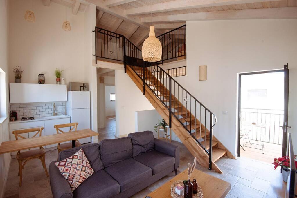 ein Wohnzimmer mit einem Sofa und einer Treppe in der Unterkunft Tavor zimmer אירוח כפרי מול נוף תבור in Daverat