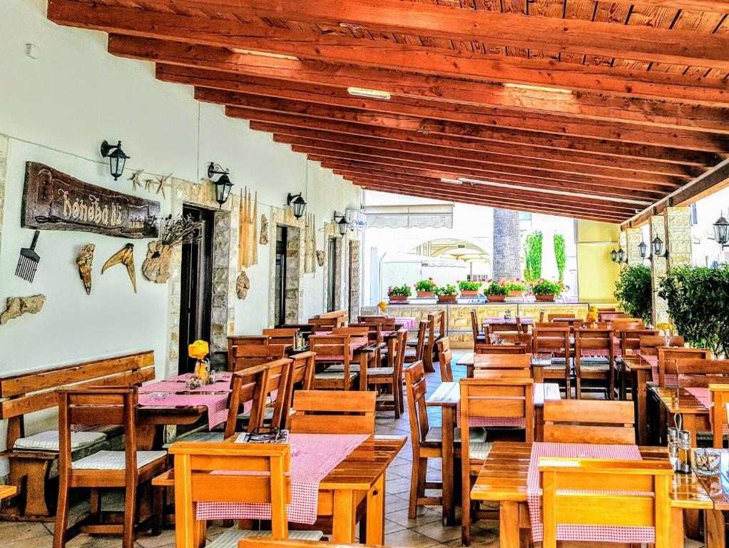 an empty restaurant with wooden tables and chairs at Villa Palčić in Novalja