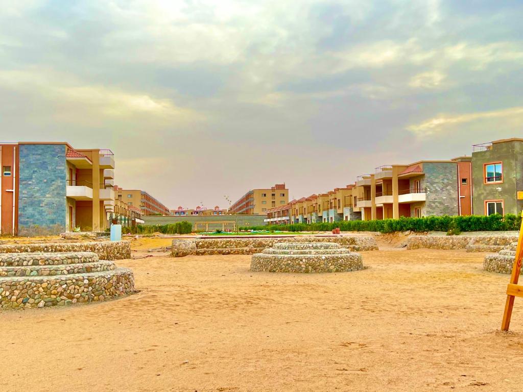 a group of rocks sitting in the sand in front of buildings at Chalet in La Jolie Marina El Ain El Sokhna - Egyptian Families Only in Ain Sokhna