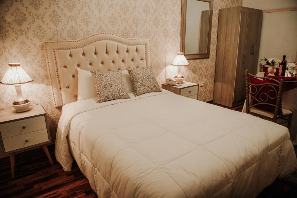 a bedroom with a large white bed with two lamps at Hotel Chavin Señorial Trujillo in Trujillo