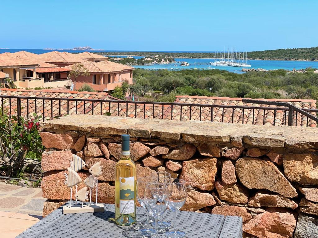 a bottle of wine sitting on a table with wine glasses at Casa Leo - Villaggio Baia De Bahas in Golfo Aranci