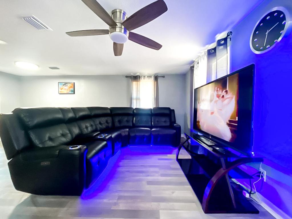 a living room with a black couch and a tv at Sarasota Modern, Spacious, Comfy, Queen Beds, Backyard Rental in Sarasota