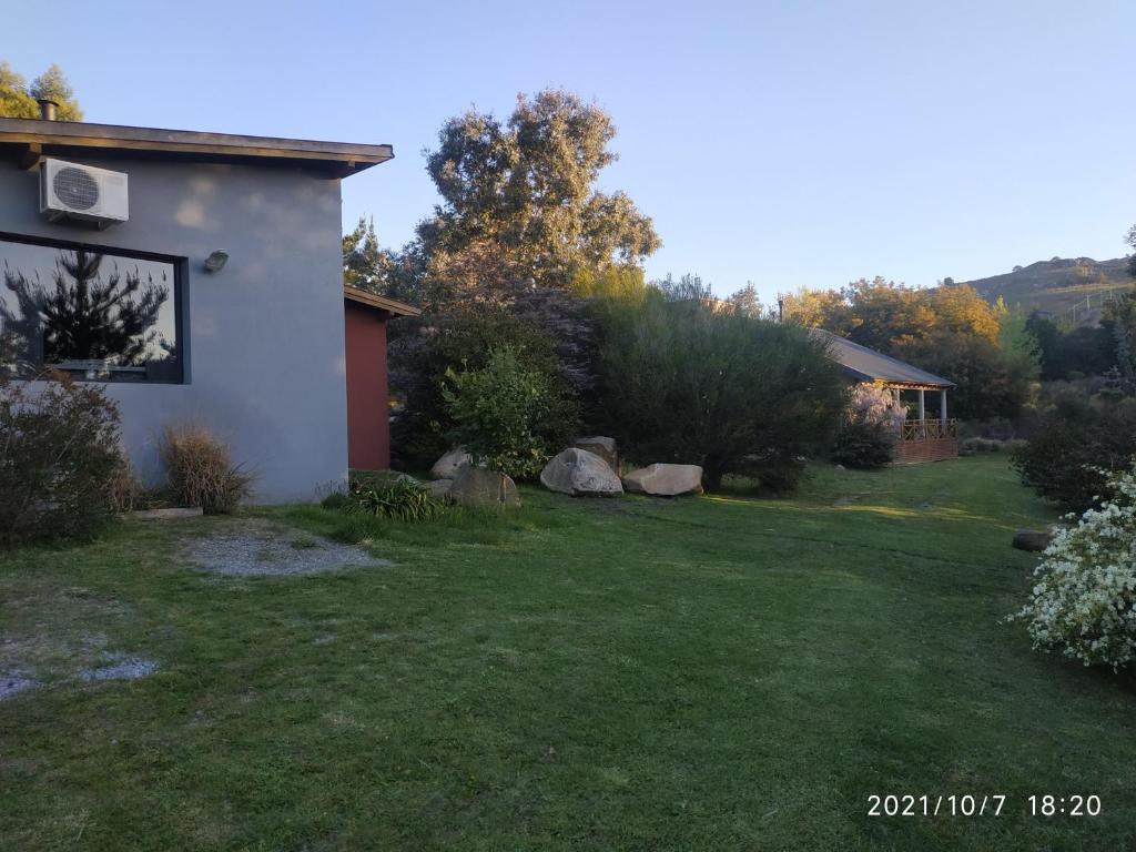 einen Hinterhof eines Hauses mit einem Garten mit grünem Gras in der Unterkunft Las Golondrinas in Tandil