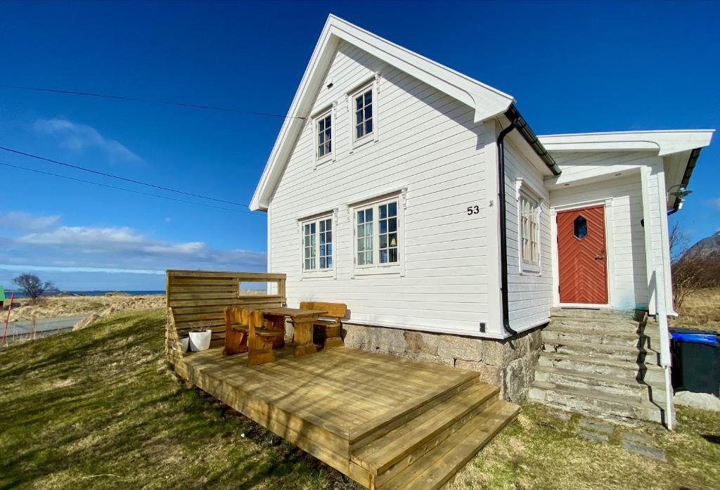 una casa blanca con una terraza de madera delante de ella en Fishermans View en Alstad