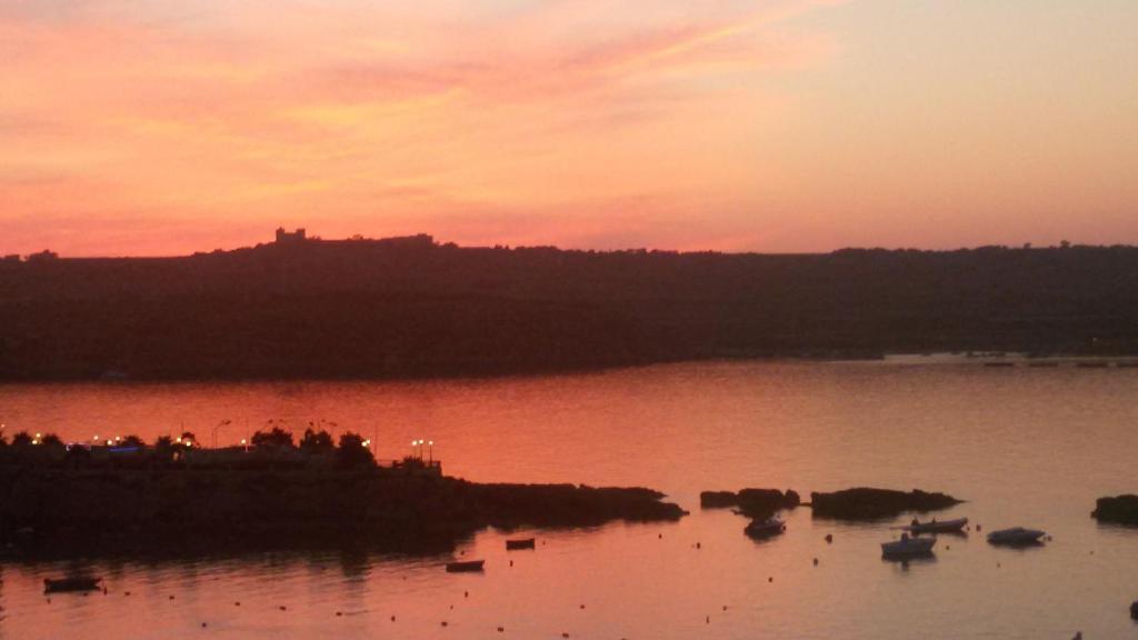 un coucher de soleil sur une étendue d'eau avec des bateaux. dans l'établissement A Seafront Home away from home, à San Pawl il-Baħar