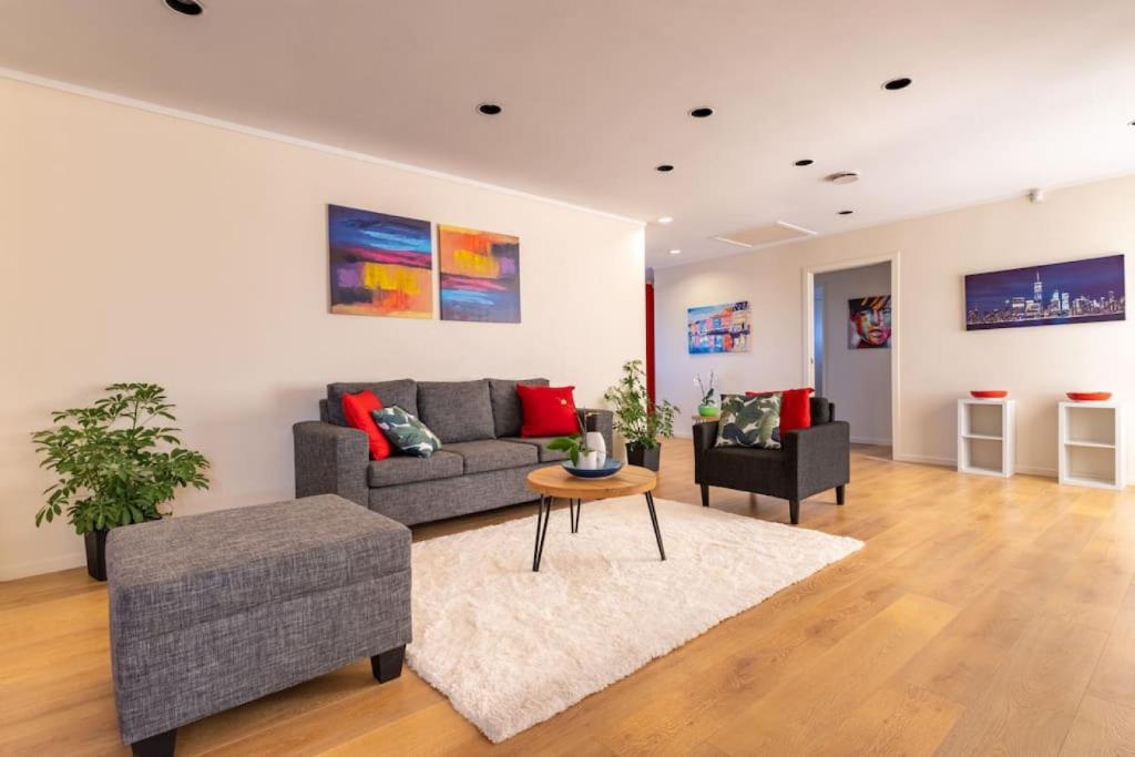 ein Wohnzimmer mit einem Sofa und einem Tisch in der Unterkunft Skyline Elegance House with Spa -Seaview - Deck in Auckland
