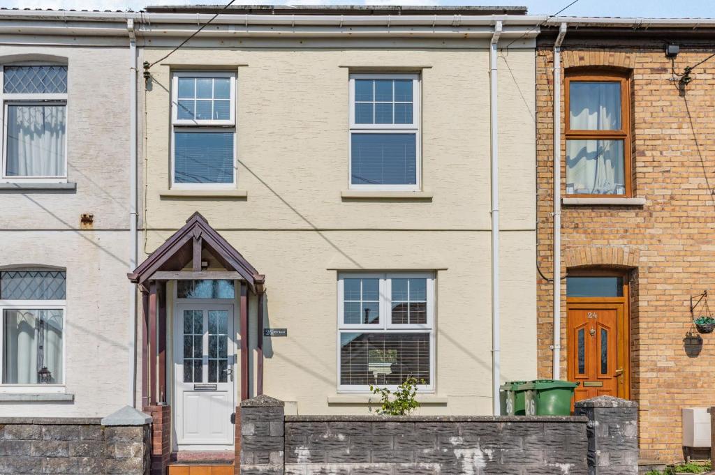 uma casa de tijolos com uma porta branca e janelas em Ty'r Ystrad em Kidwelly