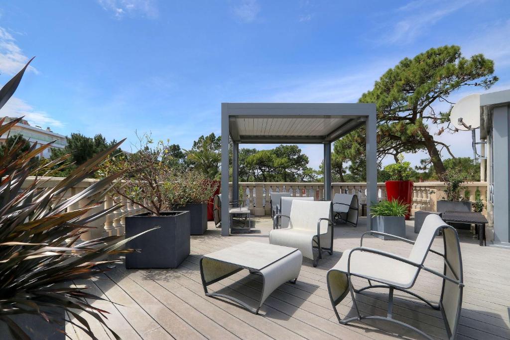 un patio con sillas, mesas y cenador en Best Western Brittany La Baule Centre en La Baule