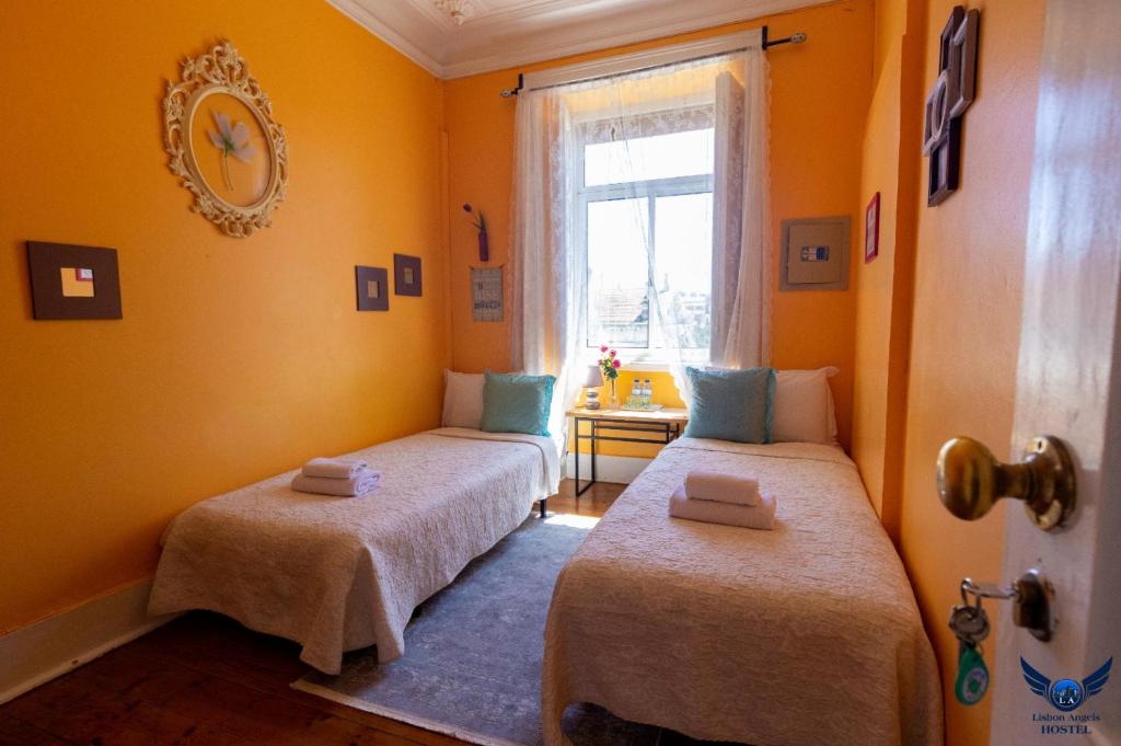リスボンにあるLisbon Angels Hostelの黄色い壁の客室内のベッド2台