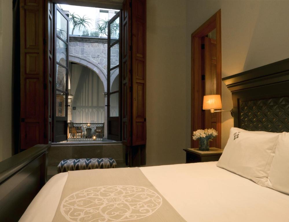 ein Schlafzimmer mit einem großen Bett und einem Fenster in der Unterkunft Casa Grande Hotel Boutique in Morelia