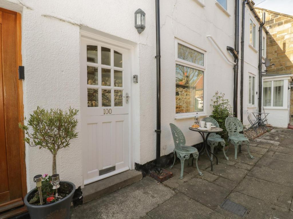 a white house with a table and chairs and a door at Cosy Cottage in Potto