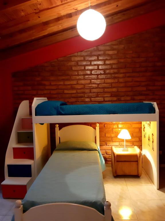 Etagenbett in einem Zimmer mit Ziegelwand in der Unterkunft POSADA DE KARMEL in Maipú