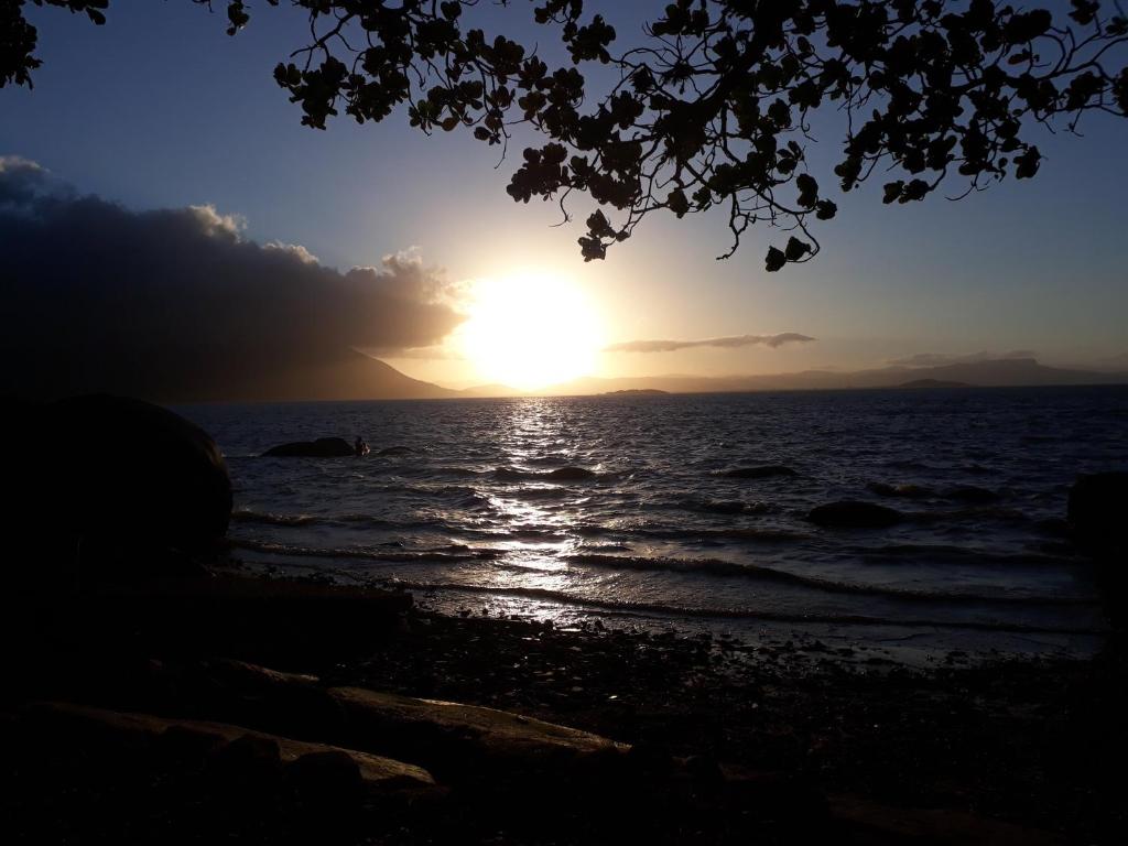 a sunset over the ocean with the sun setting at Casa Agradável, 50m da Praia Freguesia do Ribeirão da Ilha in Florianópolis