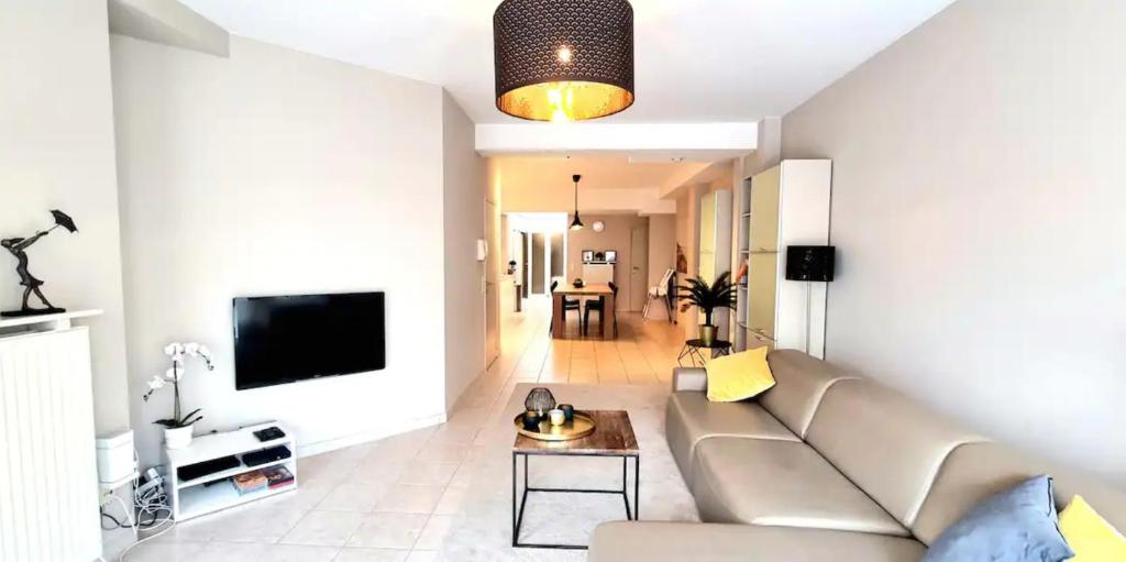 een woonkamer met een bank en een tv bij Familie appartement hartje Knokke met optie parking in Knokke-Heist