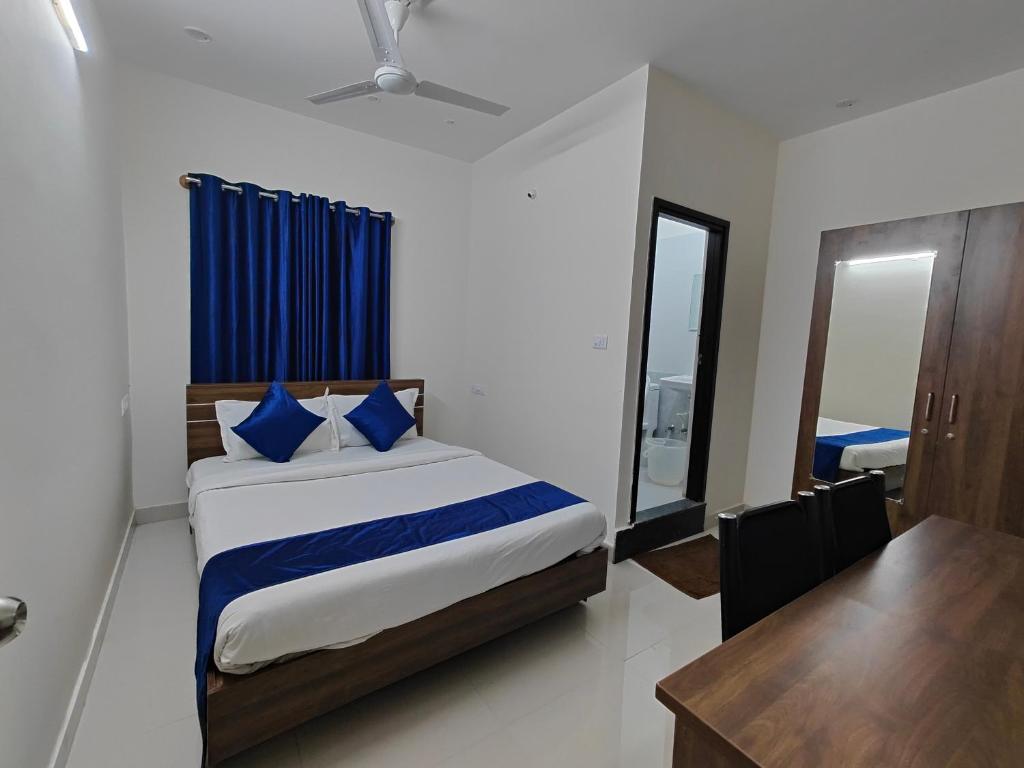 a bedroom with a bed with blue pillows and a table at The Jugglers Rest in Mysore