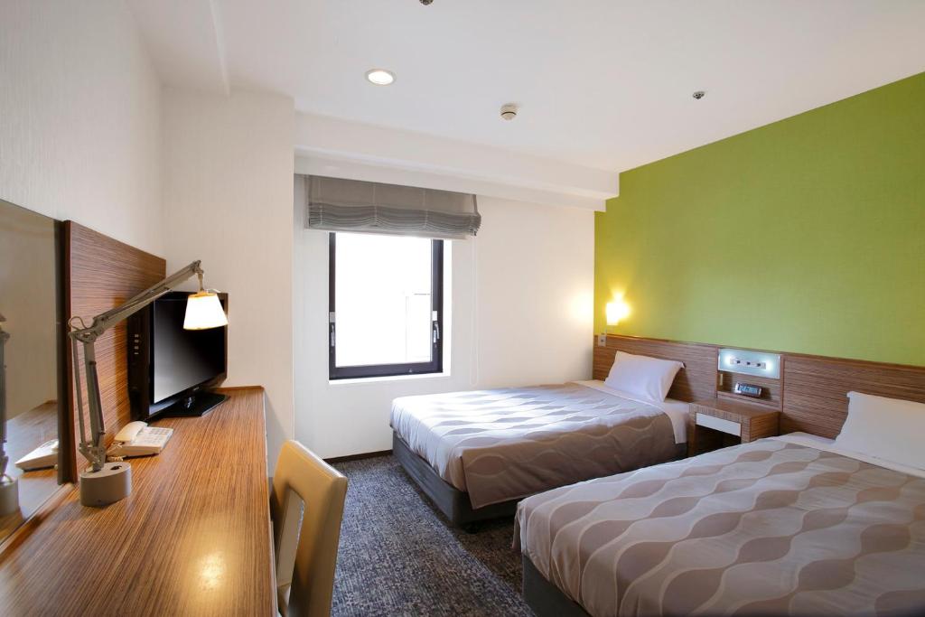 Tempat tidur dalam kamar di CYPRESS HOTEL Nagoya-eki Mae