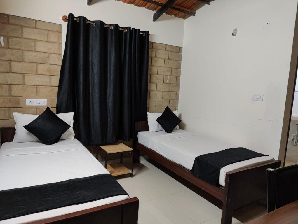 2 Betten in einem Zimmer mit schwarzen Vorhängen in der Unterkunft Minimal Poshtel in Mysore