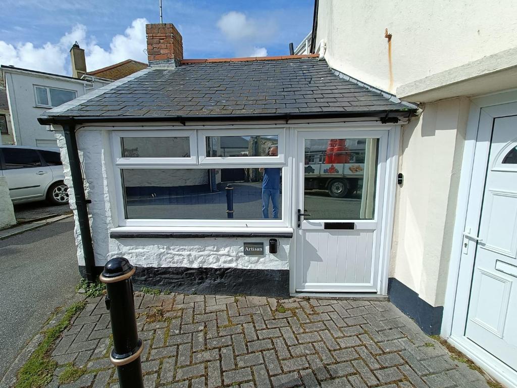 a small house with a white door on a street at Charming 1-Bed Cottage in Mullion in Helston