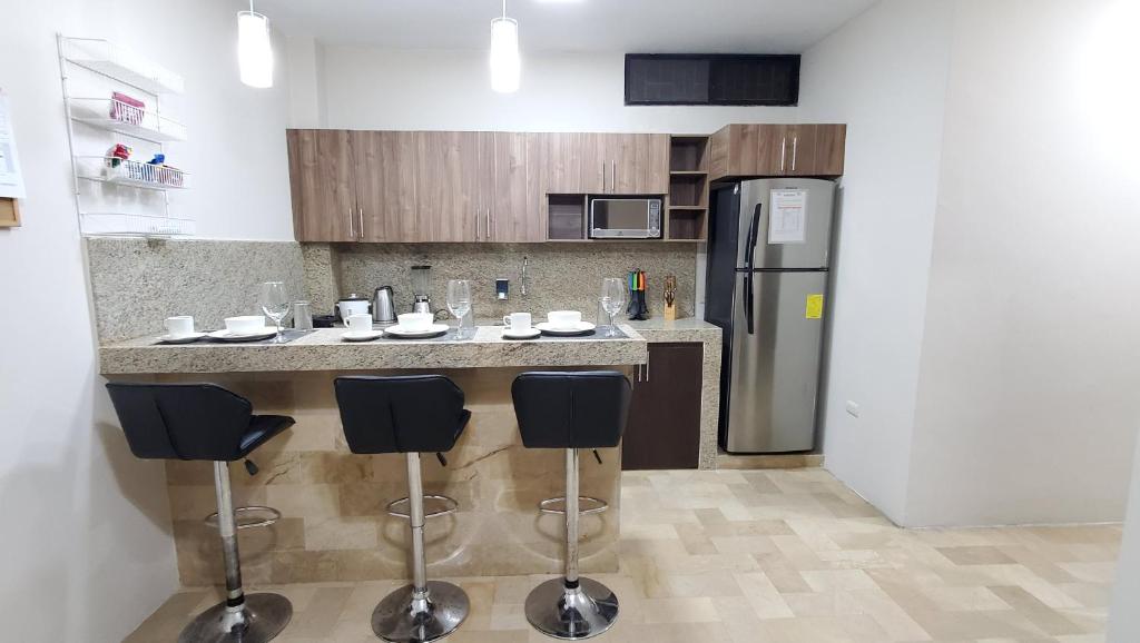 a kitchen with a counter with stools and a refrigerator at NCG SUITE SAMANES in Guayaquil