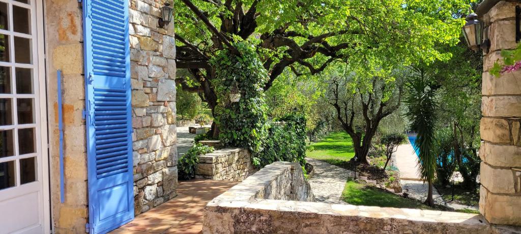 a stone house with a blue door and trees at Domaine du Paradis des Oiseaux in Mougins