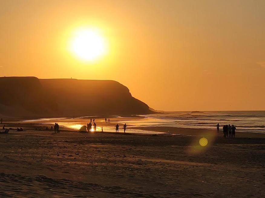 un grupo de personas en una playa al atardecer en TUPANANCHIKAMA, en Puerto Chicama