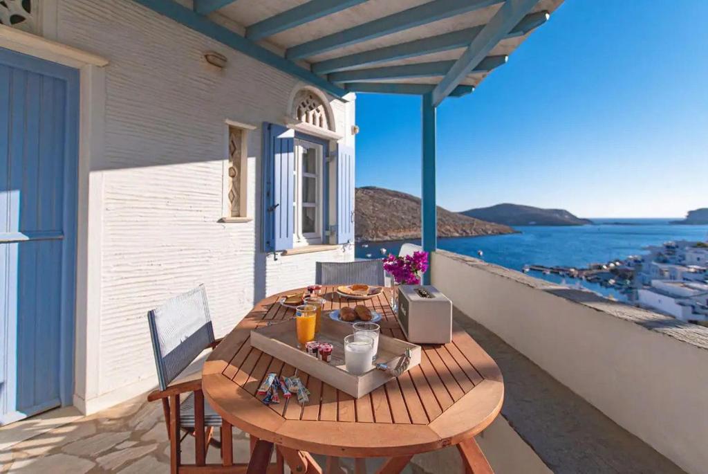 a wooden table on a balcony with a view of the ocean at Panormos Villa Tinos Greece - Traditional House in Pánormos
