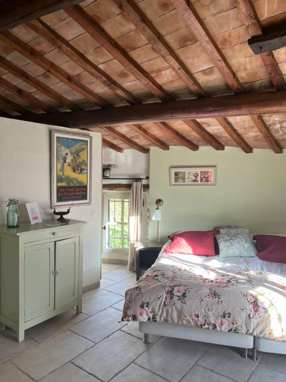 een slaapkamer met een bed en een houten plafond bij Mas Lou Parpaioun in Crestet