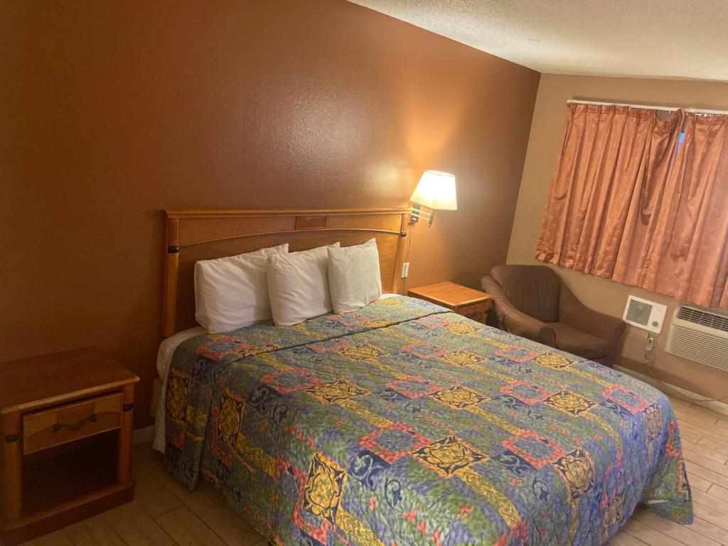 ein Hotelzimmer mit einem Bett mit einer farbenfrohen Tagesdecke in der Unterkunft Regalodge Motel in Yuma