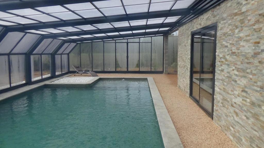 uma piscina interior num edifício com janelas de vidro em La grange de Pachon em Aurice