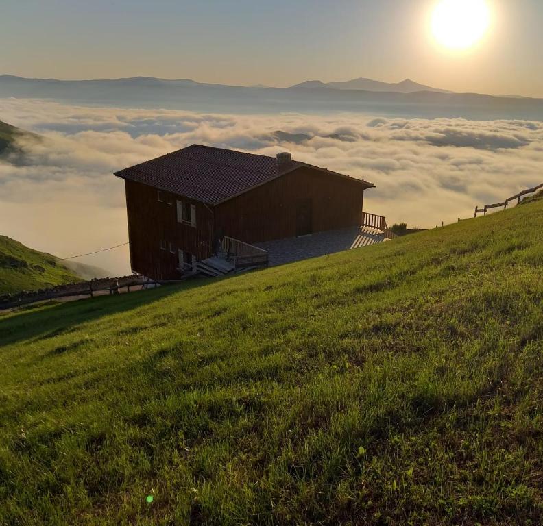 a building on top of a hill with the sun in the background at MiGRORAŞ OTEL&RESTAURANT-KARESTER YAYLASI in Uzungöl