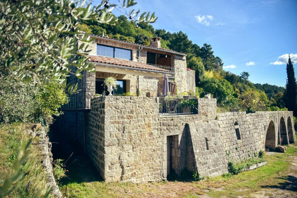 une maison au-dessus d'un mur en pierre dans l'établissement Le Domaine du Fayet, à Sanilhac