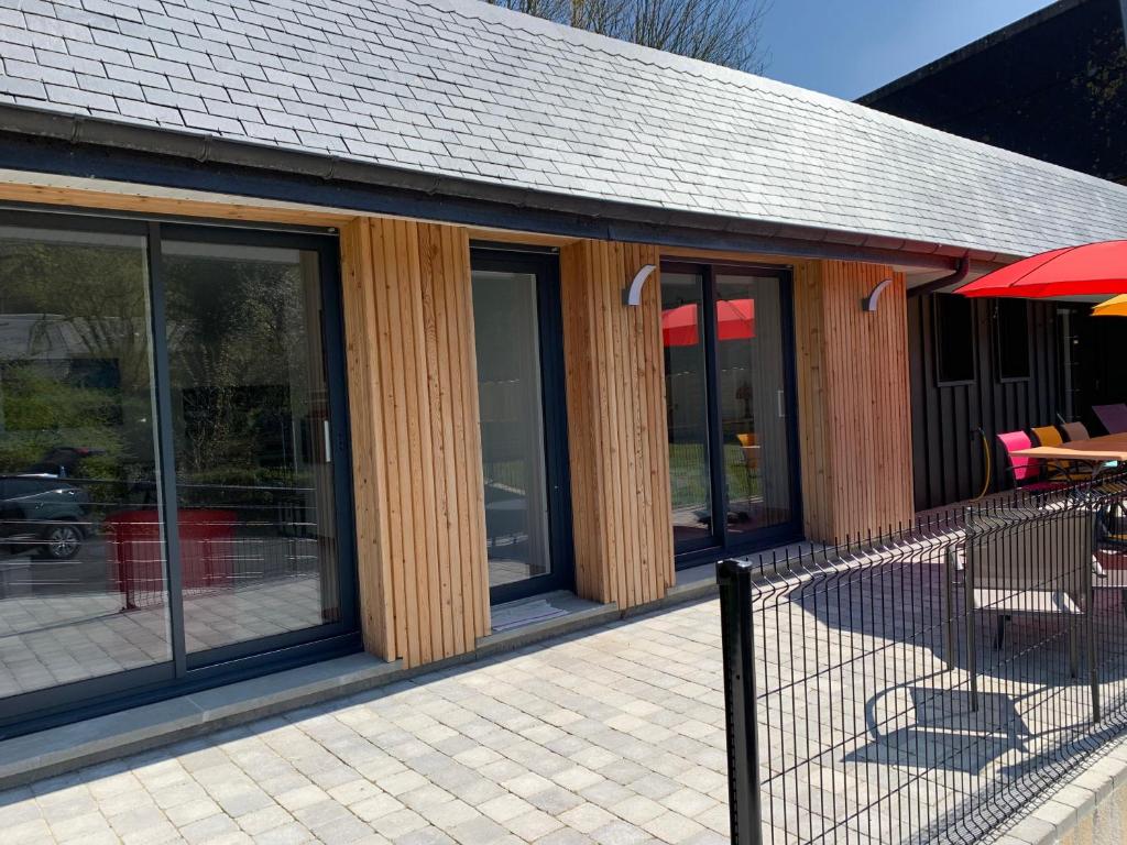 - un bâtiment avec des fenêtres en verre, une table et des chaises dans l'établissement Gites La Baie des Remparts Meublé Le Hâble d'Ault, à Ault