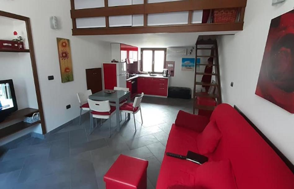 un soggiorno con divano rosso e una cucina di Appartamentino sul lago di Bolsena a Gradoli