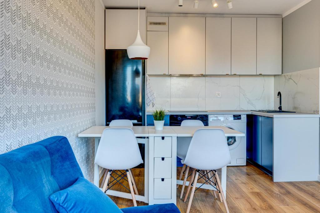 une cuisine avec un canapé bleu et des fauteuils blancs dans l'établissement Apartament Szczecin Kobalt - Urząd Miasta, à Szczecin