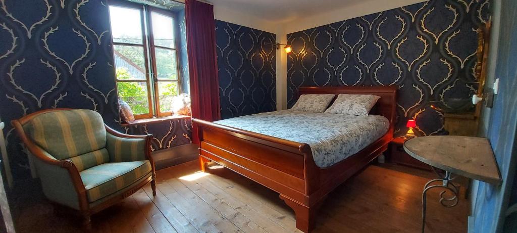 een slaapkamer met een bed, een stoel en een raam bij Chambres d'hôtes a l'étang d'Yonne in Arleuf