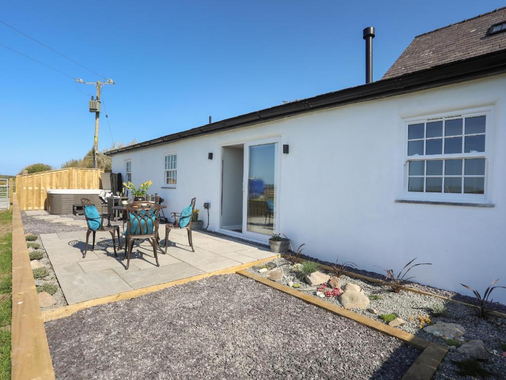 a patio with a table and chairs in front of a house at Yr Hen Laethdy in Holyhead