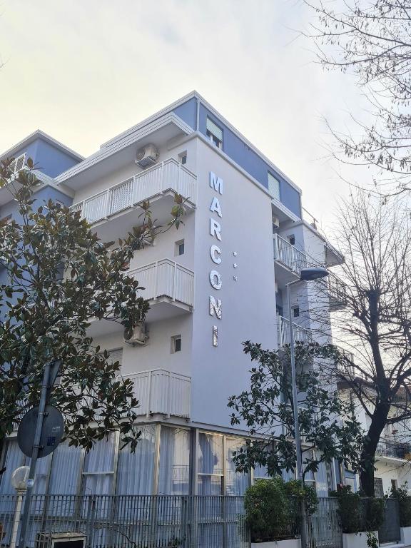 a white building with a sign on it at Hotel Marconi Miramare in Rimini