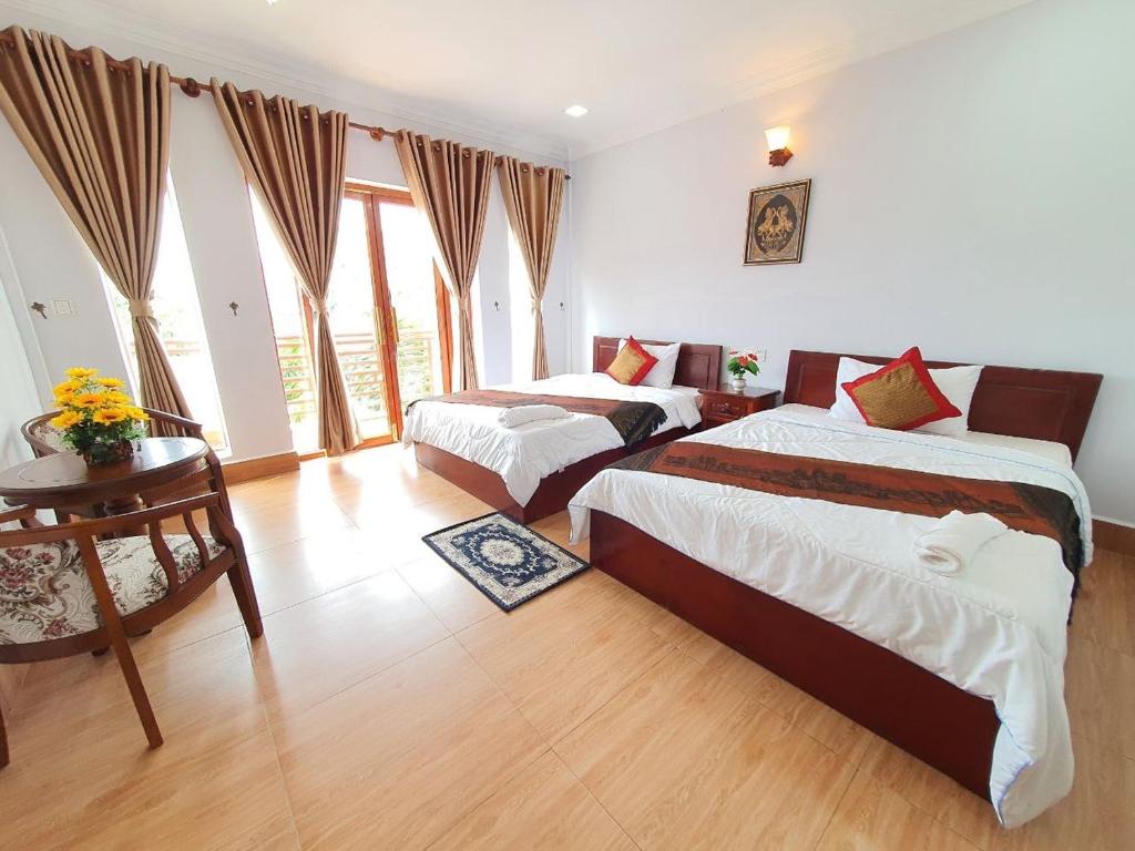 a hotel room with two beds and a table and a room at Reaksmey Meanrith Guesthouse and Residence in Sihanoukville