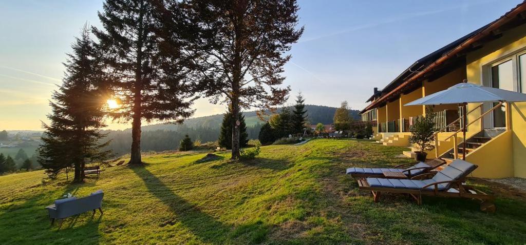 a person sitting on a bench next to a house at Dreisessel Motel in Haidmühle