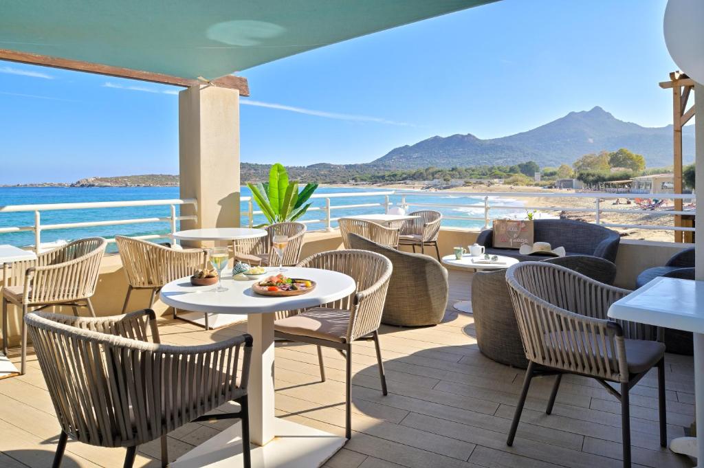 a restaurant with tables and chairs and a view of the beach at Hotel Beau Rivage in Algajola