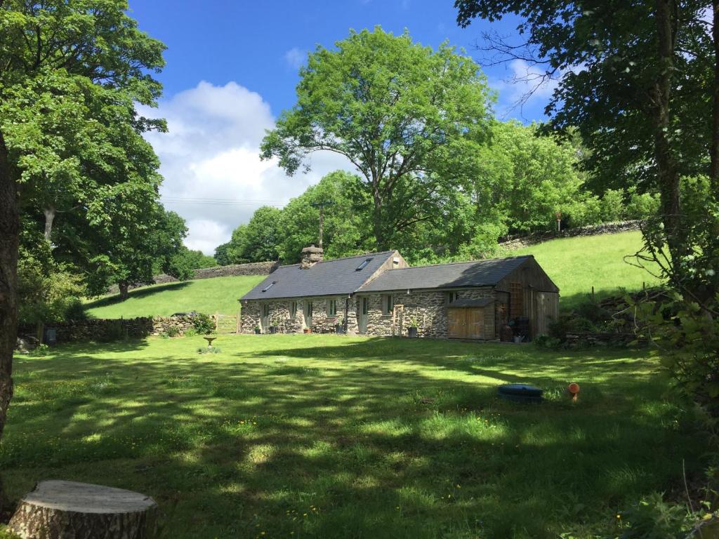an old stone barn in a field with trees at Glanrhyd cottage in Betws-y-coed