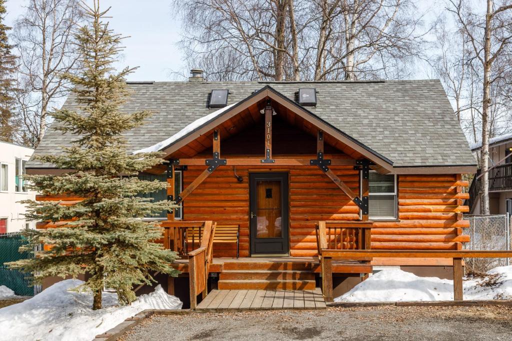 uma cabana de madeira com um alpendre na neve em Northwood Cabin em Anchorage