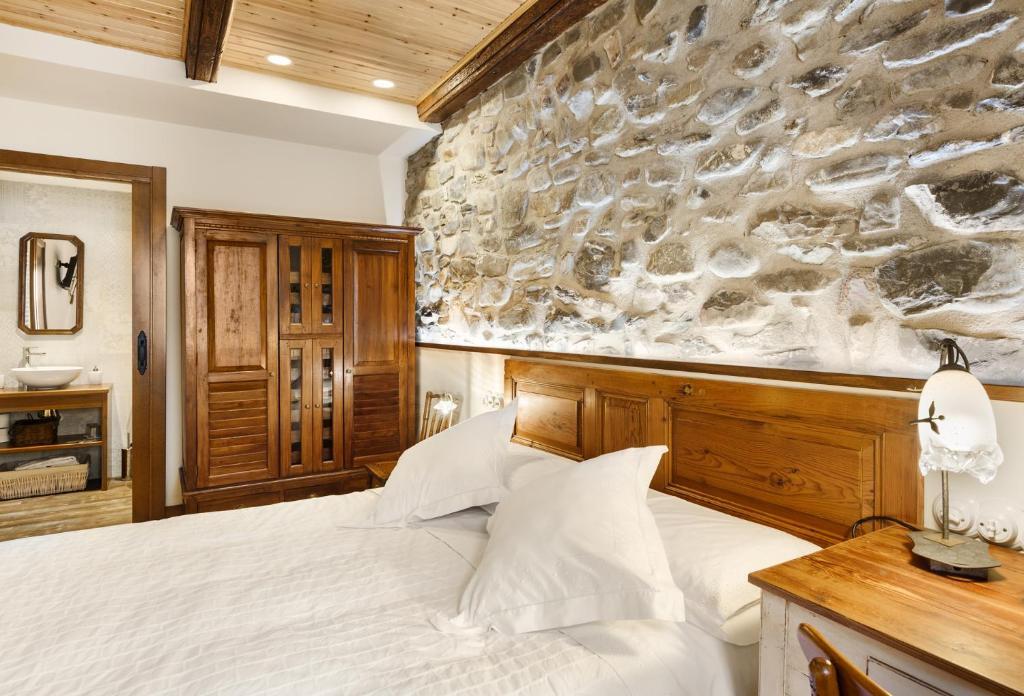 Casa Rural Francisco Mayo في إيسابا: غرفة نوم بسرير وجدار حجري