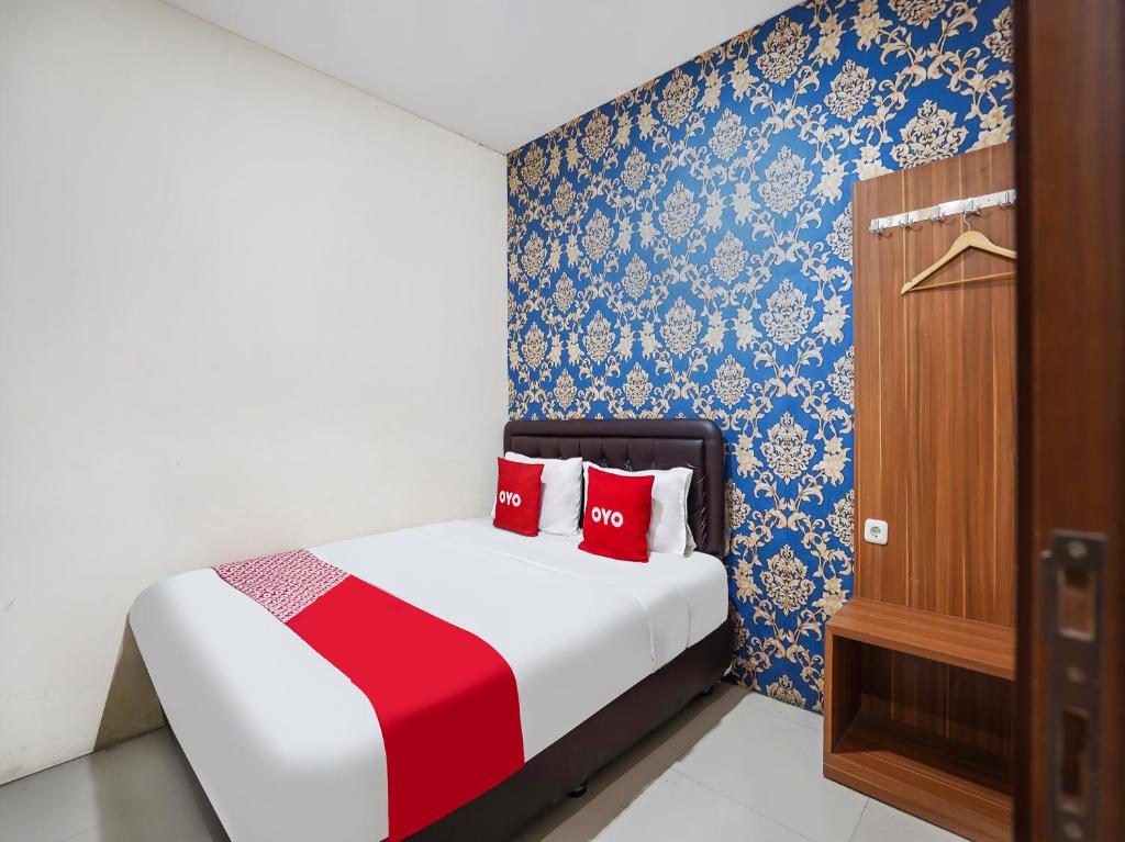 SUPER OYO 91049 D'lima Guest House Sub في Medokanayu: غرفة نوم عليها سرير ومخدات حمراء